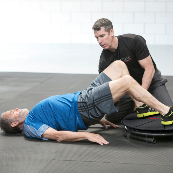 Physical therapist assists man doing an exercise on the Core-Tex Reactive Trainer